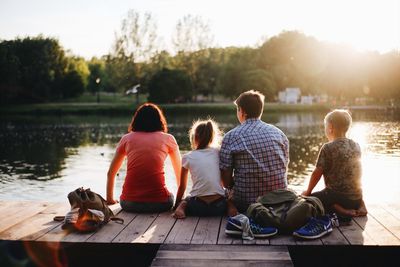 Rear view of people sitting by lake