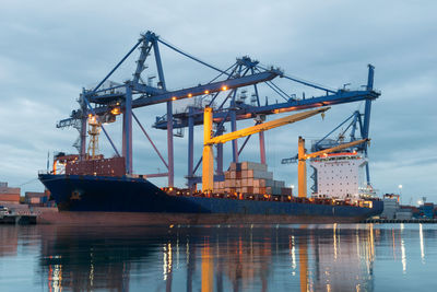 Cranes at commercial dock against sky