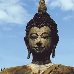 Low angle view of buddha statue against sky