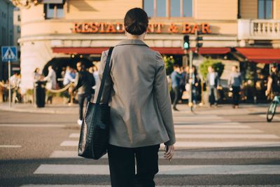 Rear view of people walking on street in city