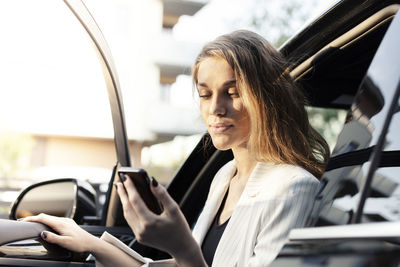 Young woman using mobile phone while sitting in car