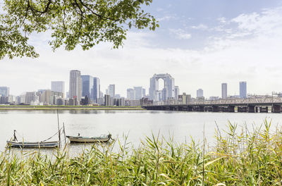 Scenic view of river by buildings against sky