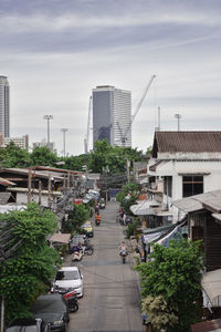 Cars on road by buildings against sky
