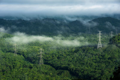 High voltage power transmission towers in fog on mountain mae moh lampang.