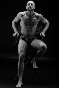 Full length of shirtless man against black background