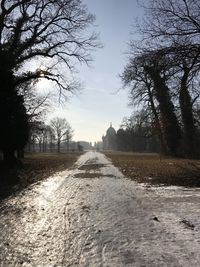 Dirt road amidst field against sky