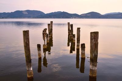 Wooden posts in lake against sky