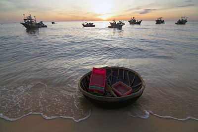 Boat moored on sea against sky during sunset