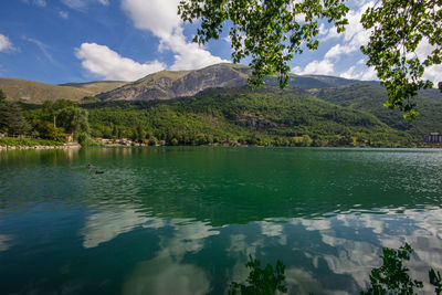 Scenic view of lake by mountains against sky