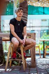 Young man sitting on chair, summertime restaurant outdoors.