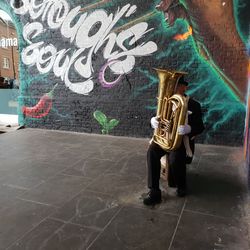 Full length of man standing against graffiti wall