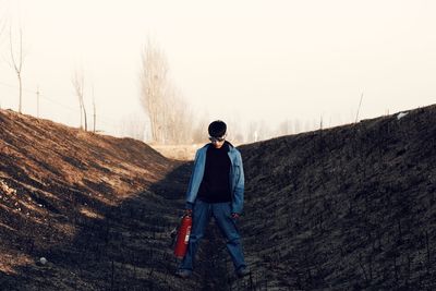 Rear view of man standing on field against clear sky