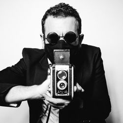 Portrait of woman photographing with camera against white background