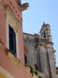 Low angle view of hand on historic building against sky