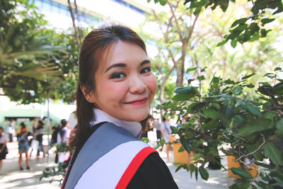 Side view portrait of smiling young woman wearing graduation gown