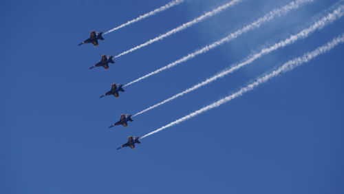 Low angle view of airshow against clear blue sky