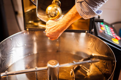 Cropped hand of barista preparing coffee in machinery at cafe