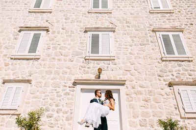 Full length of couple standing against building