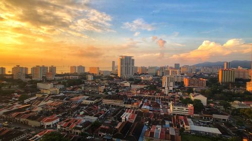 Aerial view of buildings in city against sky during sunset