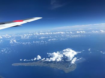 Aerial view of airplane flying over sea against sky