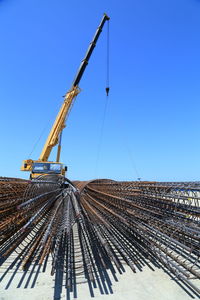 Crane at construction site against clear blue sky