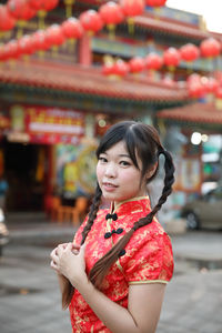 Young woman looking away while standing outdoors