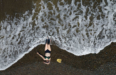 Woman with swimsuit on a sandy beach with braking waves on the shore. aerial drone photograph