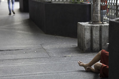 Low section of beggar sitting on footpath