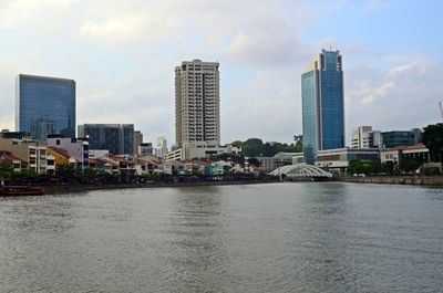 River by modern buildings against sky in city