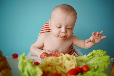 A child eats pasta with lettuce and tomatoes