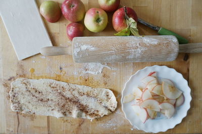 High angle view of apples with dough and rolling pin on wooden table