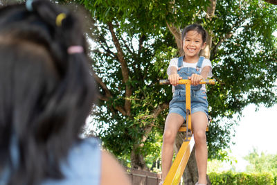 Low angle view of friends playing on seesaw at playground