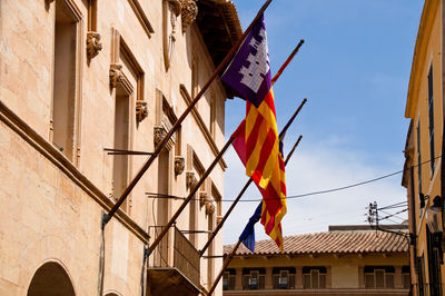 Low angle view of flags hanging on building against sky