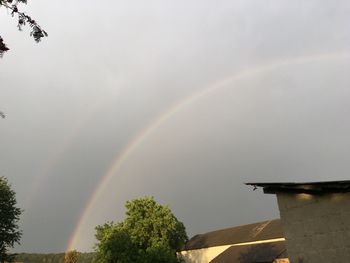Low angle view of rainbow over building against sky