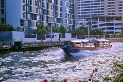 Boats moored in canal by buildings in city