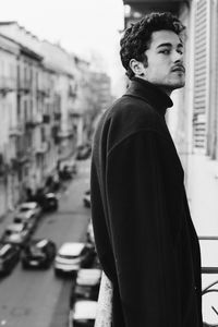 Side view of young man standing on street in city