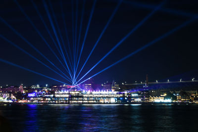 Illuminated bridge over river against sky at night