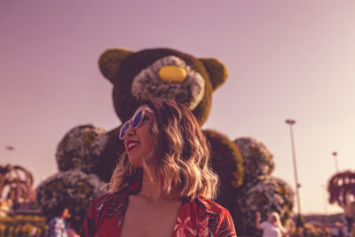 Portrait of smiling young woman against sky