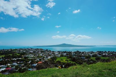 Scenic view of sea by townscape against sky