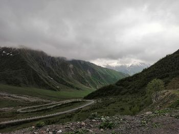 Scenic view of road by mountains against sky