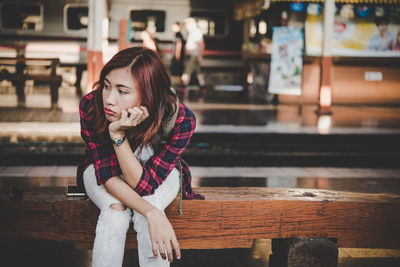 Young woman on seat at railroad station platform