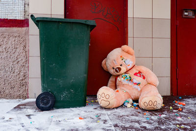 A gutted stuffed teddy bear lies torn apart by a dumpster