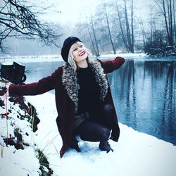 Young woman standing by frozen lake during winter