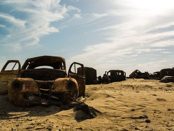 Abandoned car on beach against sky