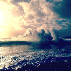 Sea waves against cloudy sky on sunny day