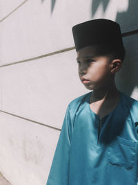 Boy wearing traditional cap by wall