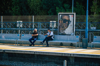 People sitting on bench by railing