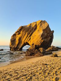 Rock formation on beach against clear sky