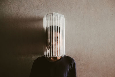 Boy wearing air bubble wrap against wall at home