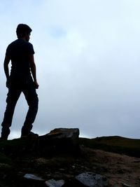 Man standing on rock against sky